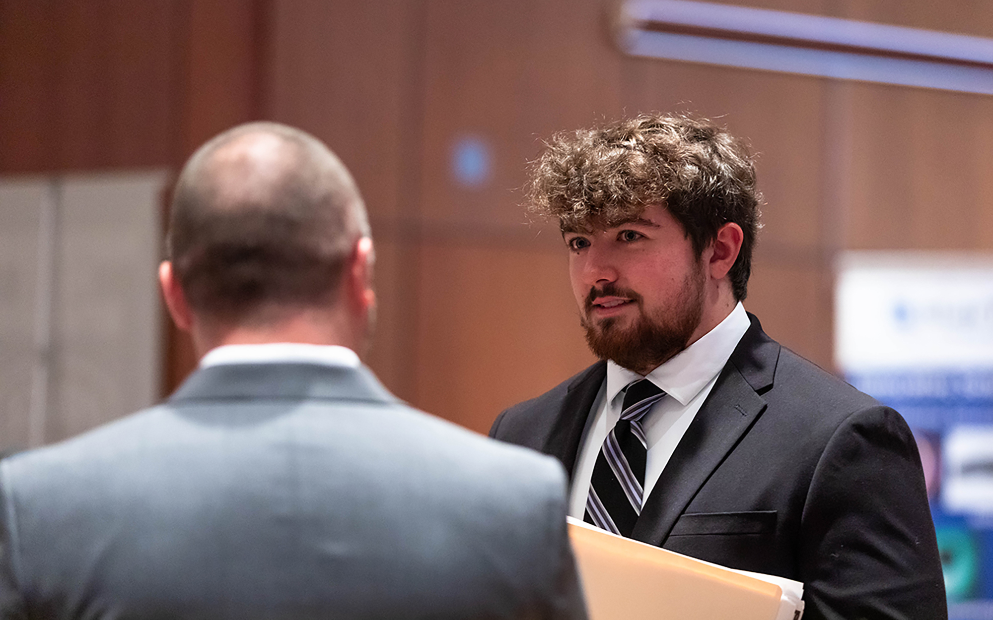 SIU student in a suit talks with a potential employer during a Job and Internship Fair